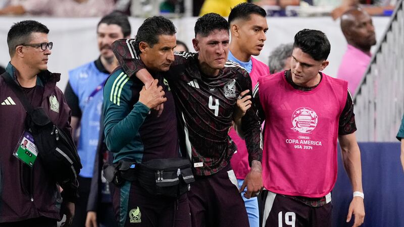 El volante mexicano Edson Álvarez (centro) se retira lesionado durante el partido contra...