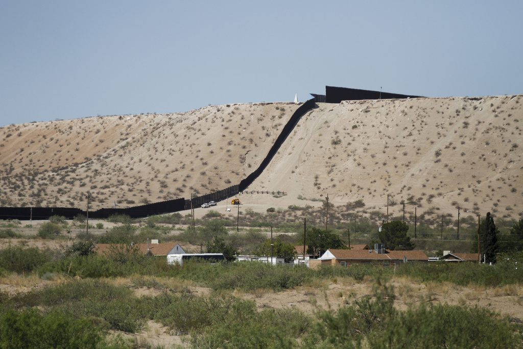 Vehículos de la Patrulla Fronteriza recorren una cerca de acero en la frontera suroeste con...