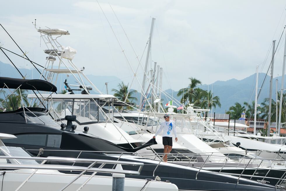Un hombre cubre una ventana en un barco mientras el huracán Simón se acerca a Puerto Vallarta,...